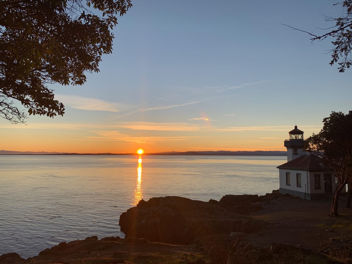 A quiet sunset over the sea, with Lime Kiln Point Lighthouse standing in silhouette—still and steady, like a memory that stays with you.